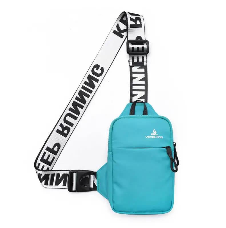 Turquoise blauwe schoudertas met een groot voorvak en ritssluiting, voorzien van een brede, verstelbare schouderband met zwart-witte tekst 'KEEP RUNNING'. Compacte en sportieve tas, perfect voor elke gelegenheid.