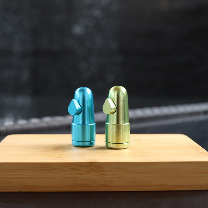 metalen mini doseer bullets in verschillende kleuren (blauw, groen, rood, zwart en goud), geschikt voor het discreet doseren van poeders of kruiden, weergegeven met een open bullet om de onderdelen te tonen.