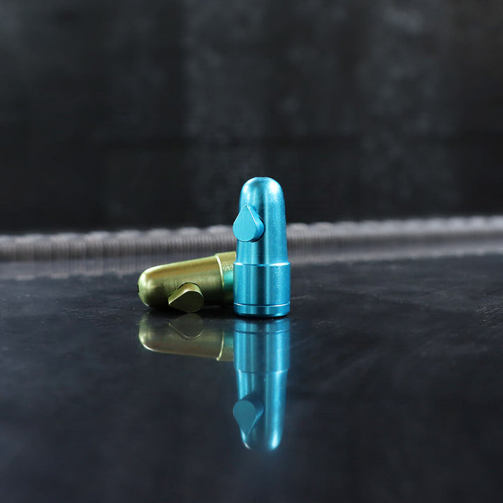 metalen mini doseer bullets in verschillende kleuren (blauw, groen, rood, zwart en goud), geschikt voor het discreet doseren van poeders of kruiden, weergegeven met een open bullet om de onderdelen te tonen.