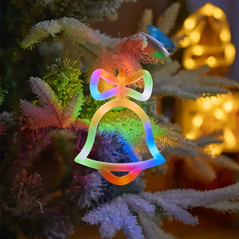 Neon kerstbel met regenboogkleuren, gehangen in een kerstboom, sfeervol verlicht tegen een warme achtergrond.