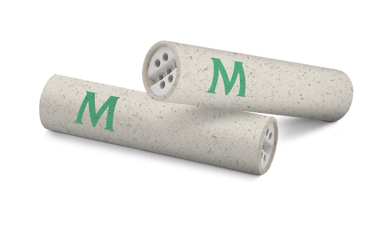 Close-up van twee Mascotte Hemp Active Slim Filters gemaakt van henneppapier, met groene 'M' opdruk. Deze duurzame filters bevatten keramische kapjes voor een pure en comfortabele rookervaring.