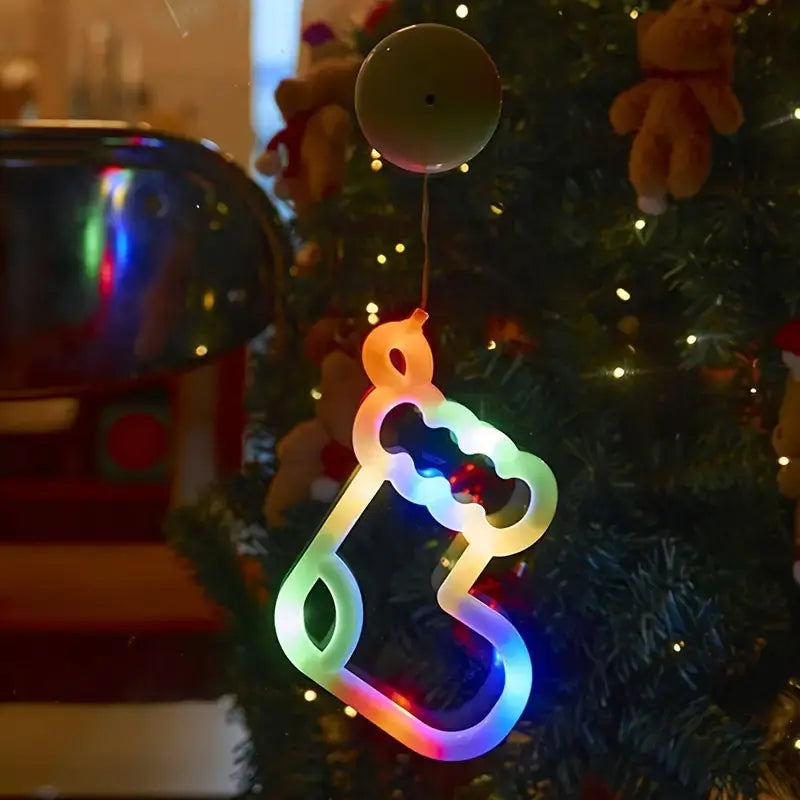 Neon kerstsok in regenboogkleuren, opgehangen aan een kerstboom, verlicht tegen een gezellige kerstachtergrond.