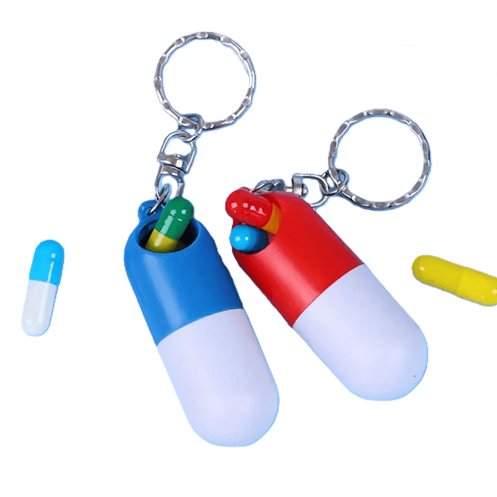 Capsulevormig pillendoosje met sleutelhanger in rood en blauw, met eenvoudig draai-mechanisme om te openen en te sluiten