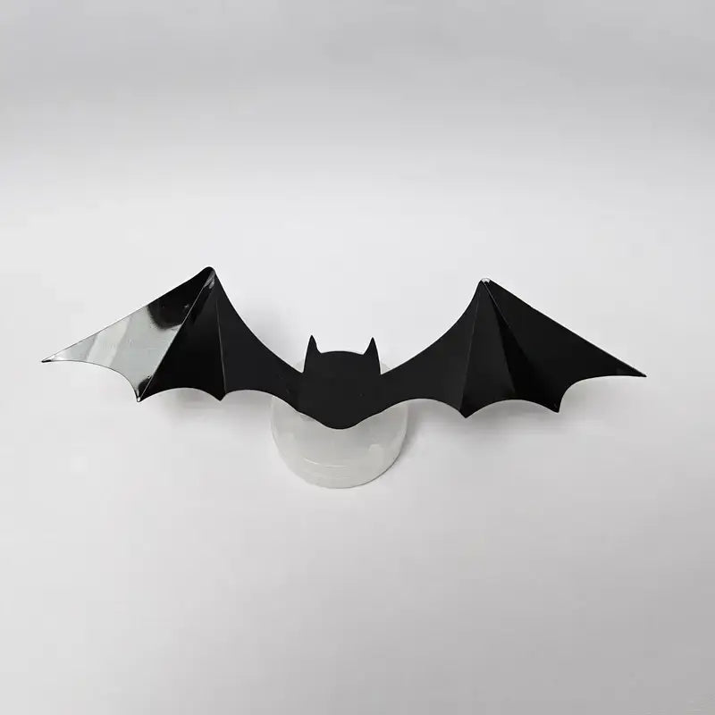 Zwarte plastic vleermuis met een LED-lampje erachter op een witte achtergrond, perfect voor Halloween decoratie.